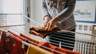 Woman folding clothes drying on a clothes horse.