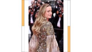 Brie Larson wears a gold dress as she attends the "Jeanne du Barry" Screening & opening ceremony red carpet at the 76th annual Cannes film festival at Palais des Festivals on May 16, 2023 in Cannes, France.