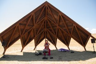 Cellist performs beneath wooden canopy of Geode at Tippet Rise