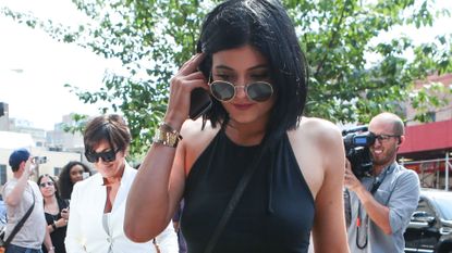 Kylie Jenner on phone with Kris Jenner behind