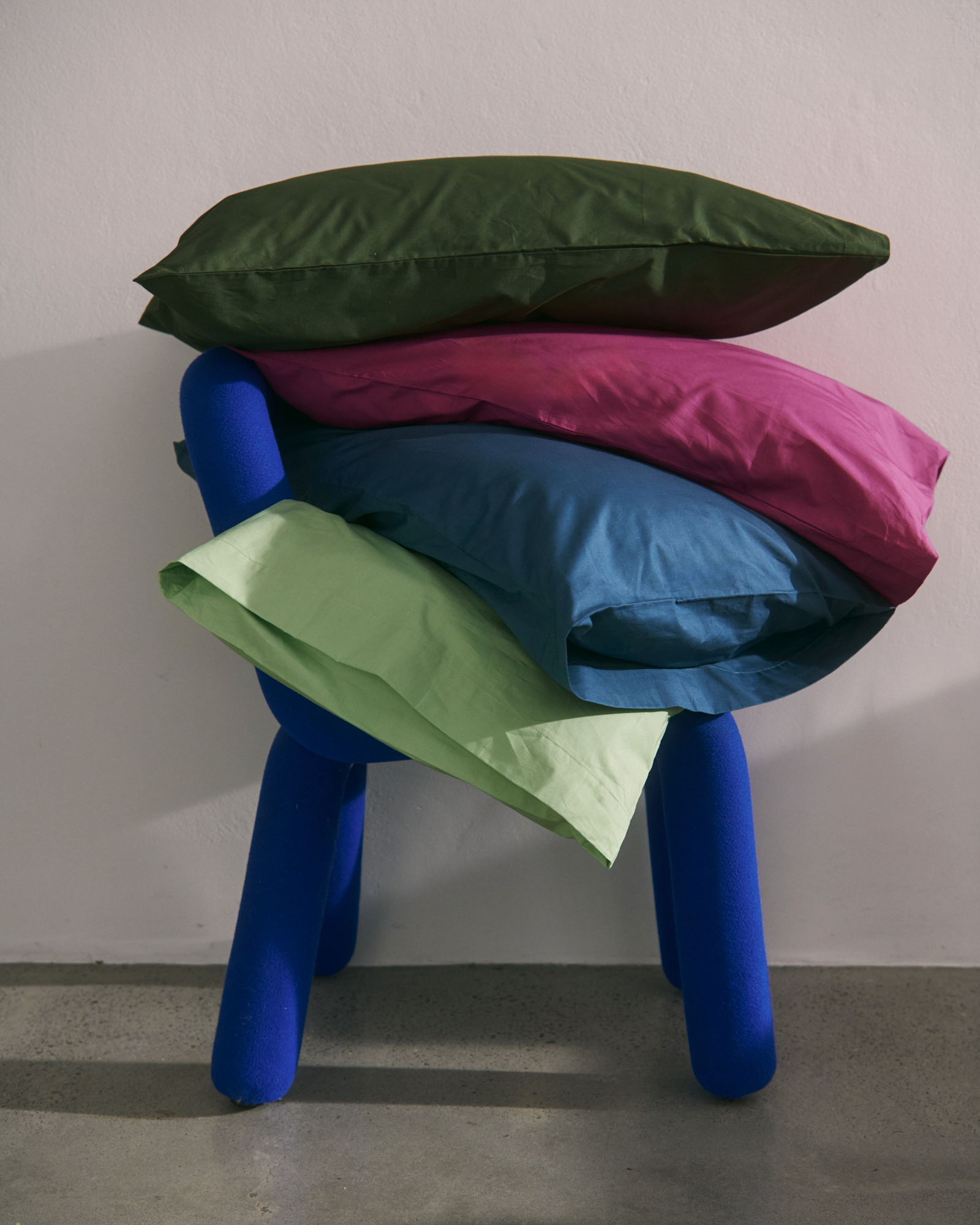 green, pink and blue pillows on a royal blue chair