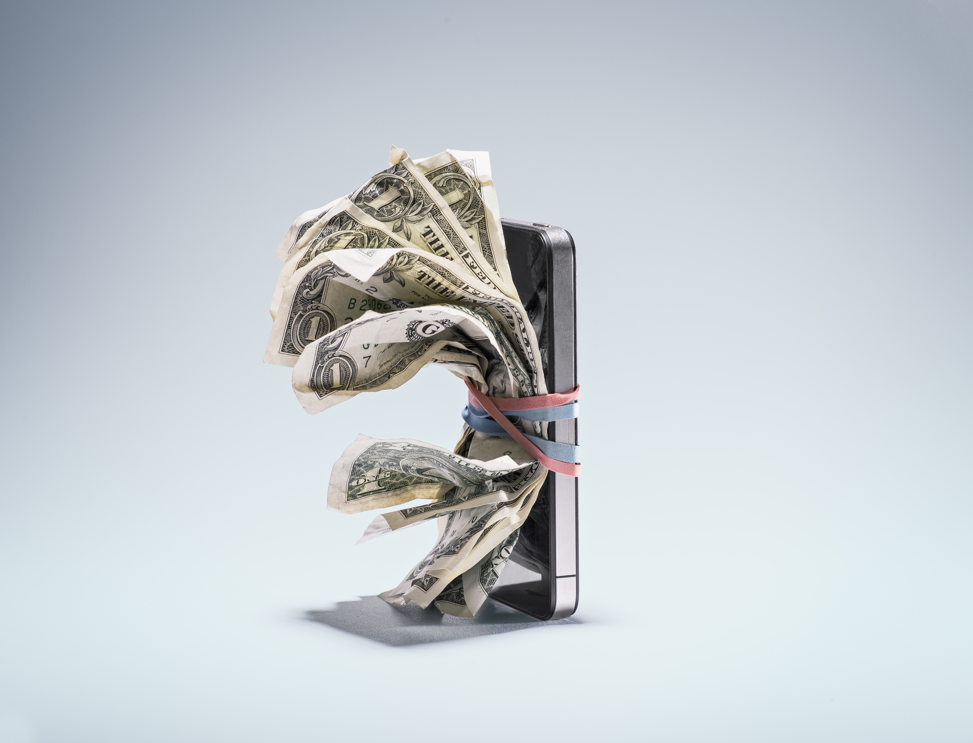 A cell phone with money attached to it by rubber bands