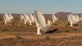 large white radio dishes point to the sky in the desert