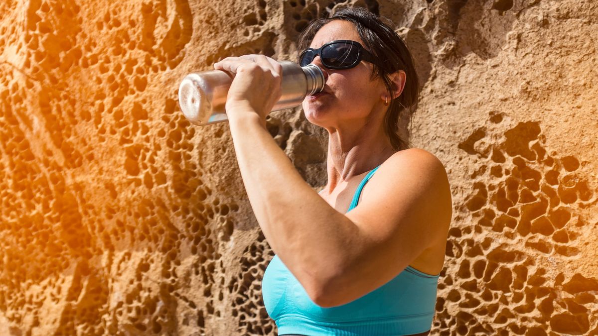 how to exercise in the heat: woman drinking from a water bottle