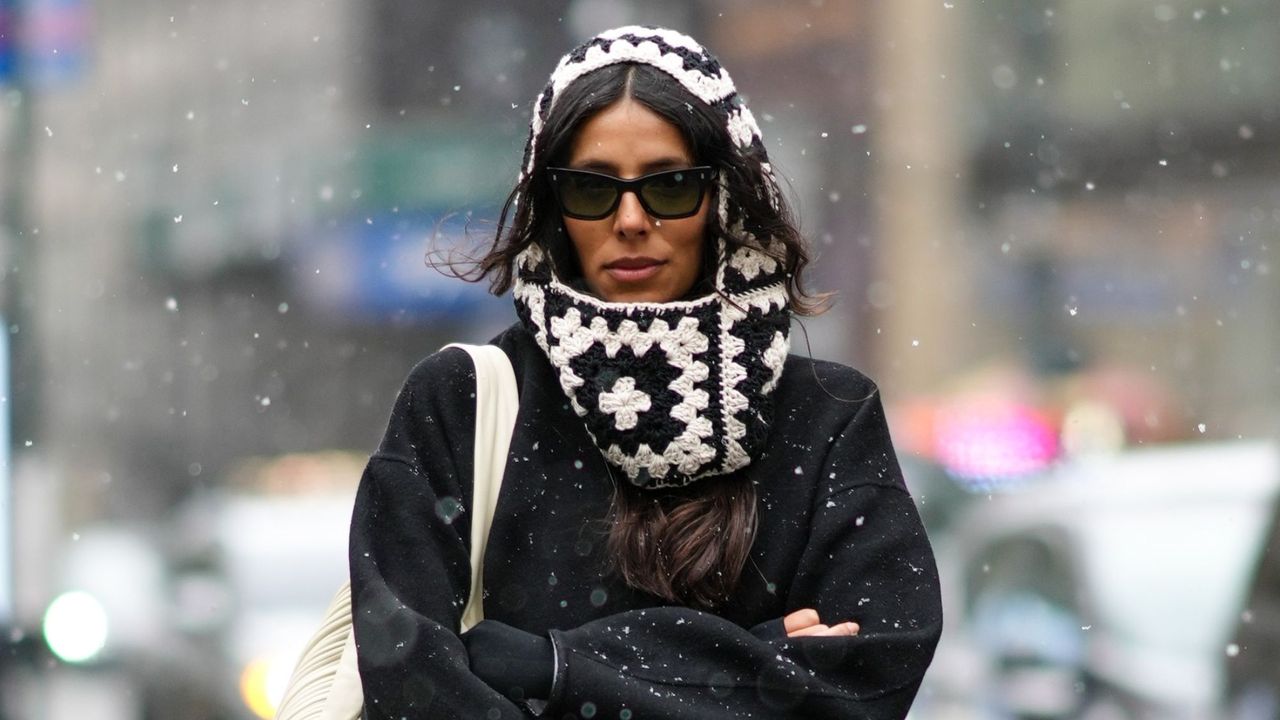 Woman walking through snow, wearing a black and white knitted hood and sunglasses - kiehls ultra facial cream