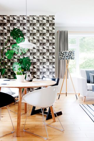 The dining area of an open plan living space, with geometric wallpaper