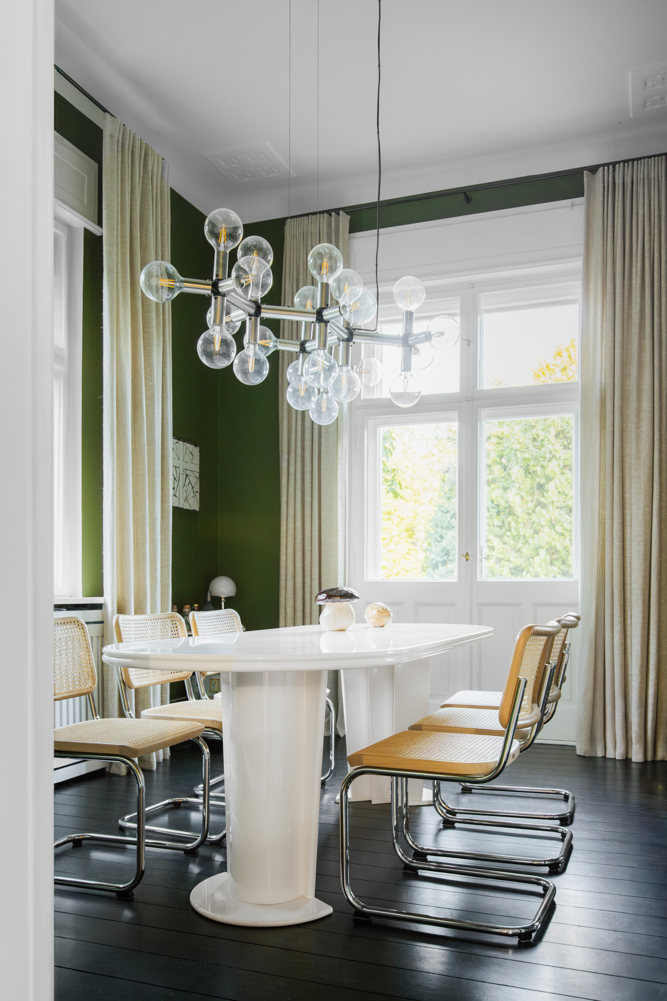 Green dining room with white gloss table, chrome tube chairs and globe chandelier
