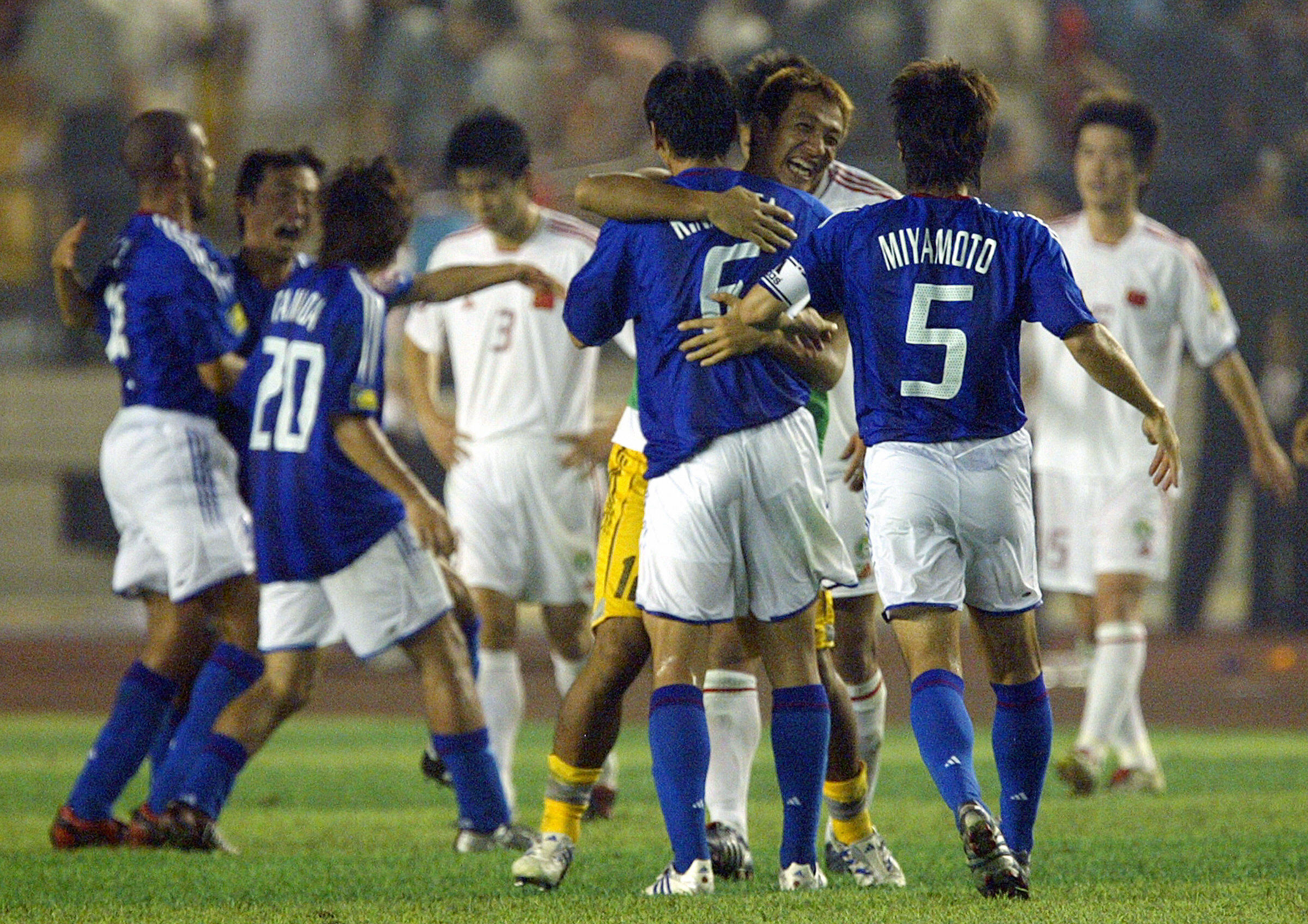 China players look dejected as Japan's footballers celebrate their Asian Cup final win in August 2004.