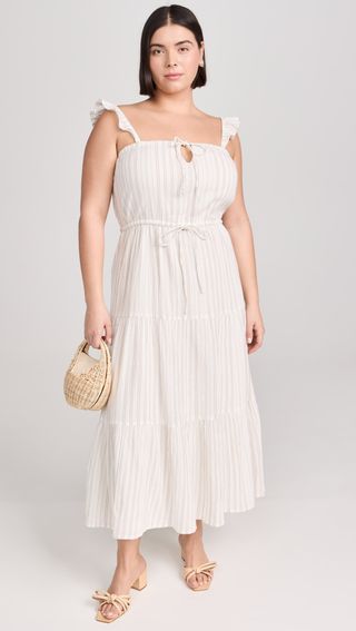 model wears white dress and is carrying a straw colored handbag