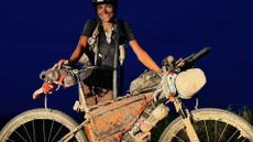 Austin Killips standing behind her bike at nighttime during her Tour Divide journey in 2024.