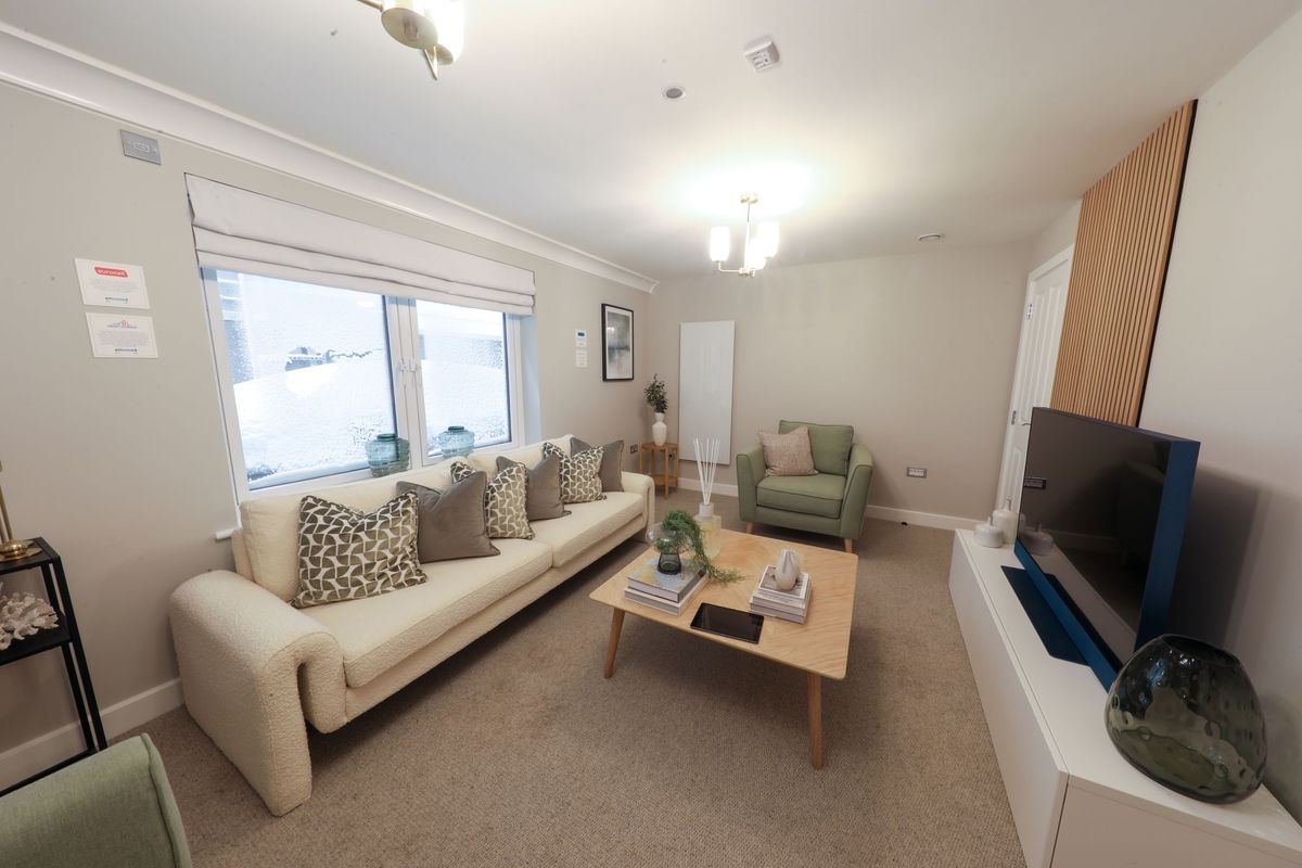 A sofa to the left of the image and a television to the right in a living room inside the newbuild