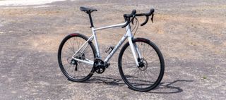 A white specialized Allez Sport stands on rocky ground