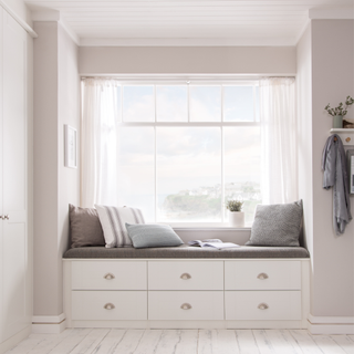 a bedroom bay window with built in storage below painted white