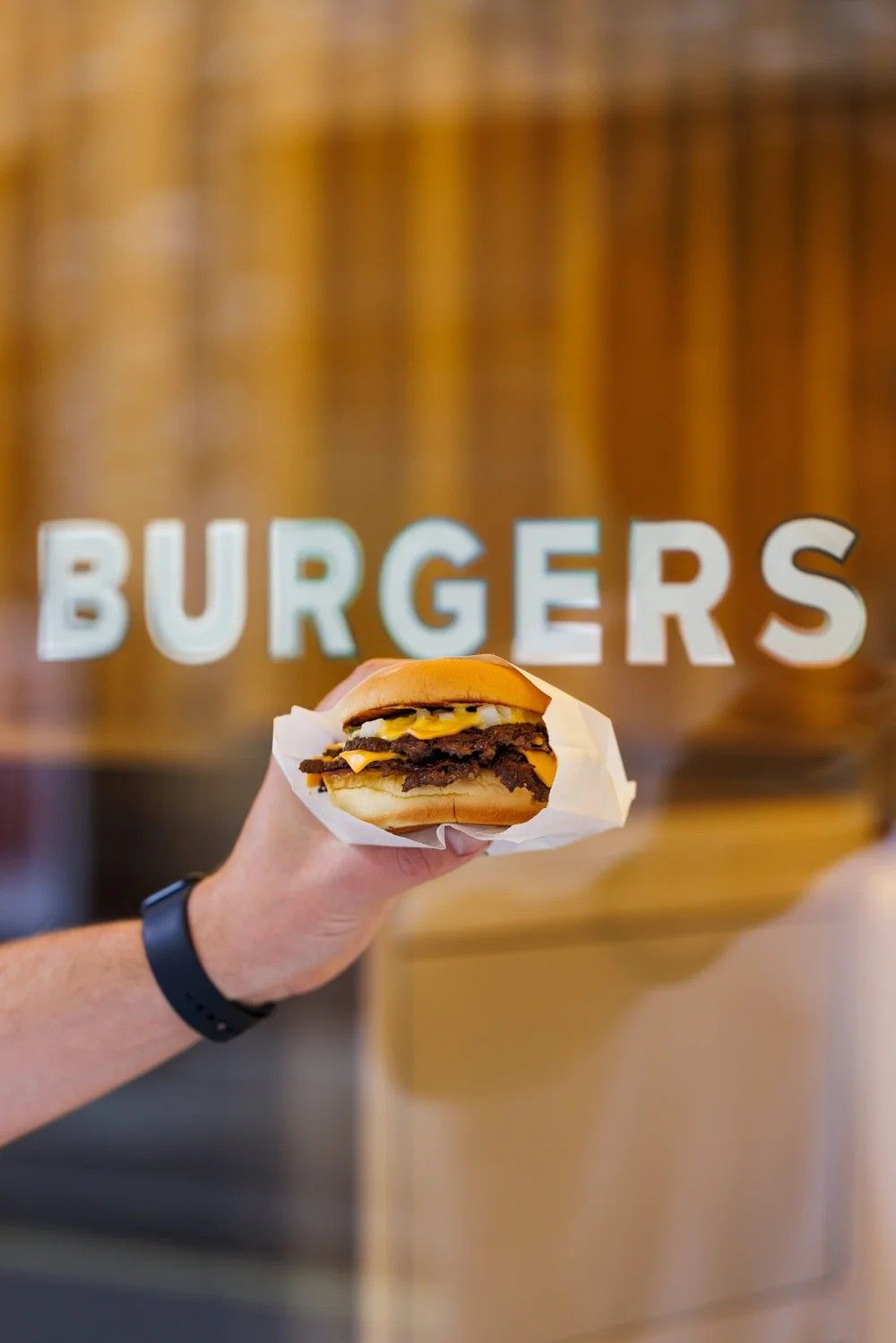 A yellow-tinted burger chain&#039;s shop front features a slightly spaceship-like look, with oblong windows, plump akwinings, red brick walls, and a warm atmosphere inside.