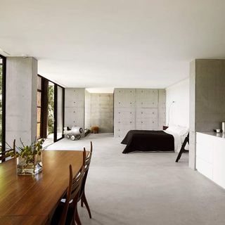 bedroom with concrete flooring and white roof with wooden table