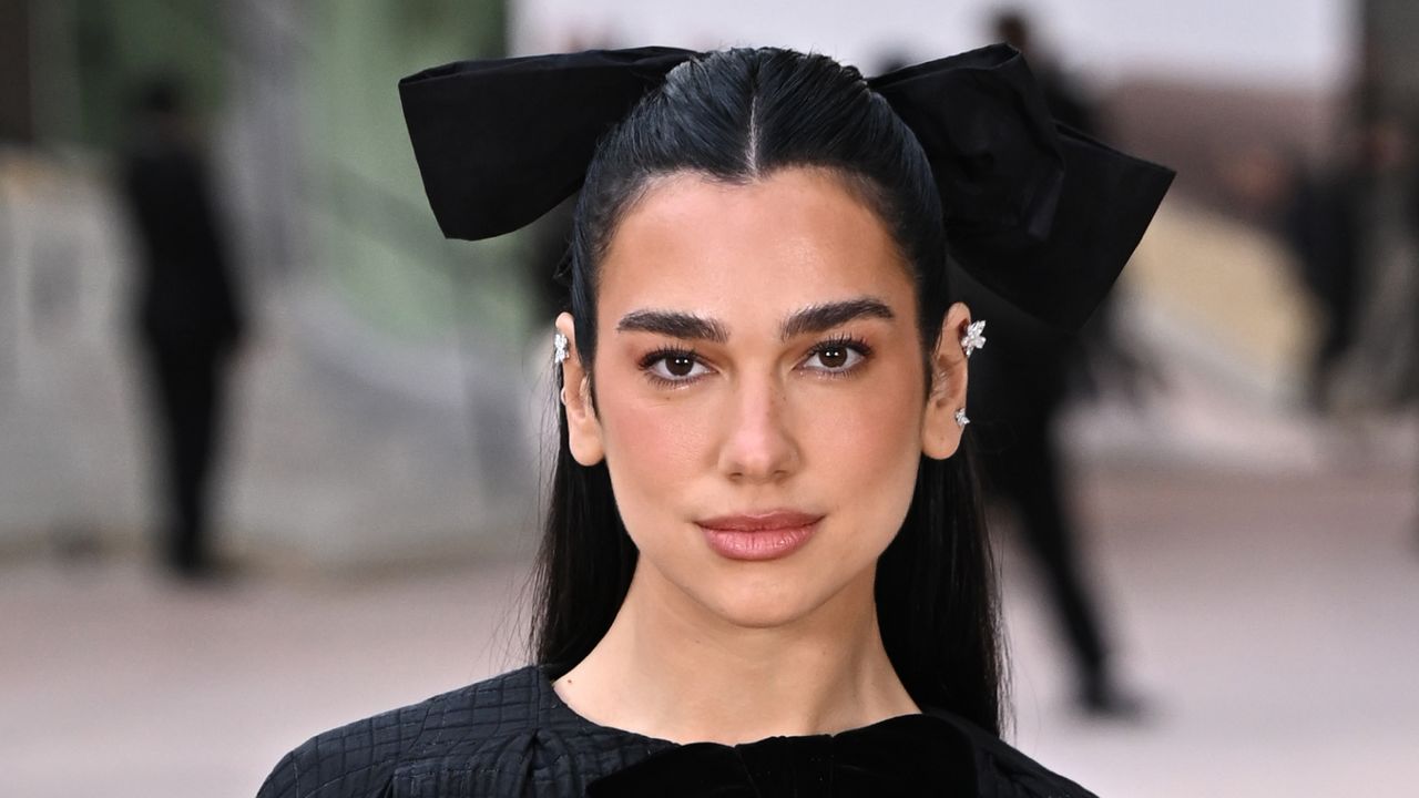 Dua Lipa at the chanel fashion show wearing a balletic bow in her hair