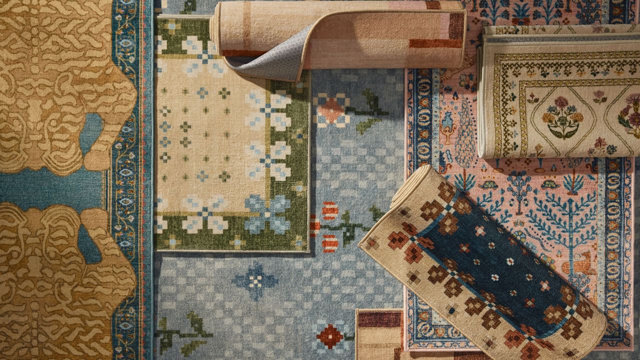 Image from above of a bunch of different patterned, colorful rugs layered on top of one another.