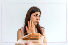 Woman unhappy and turning her hand up at a plate of bread