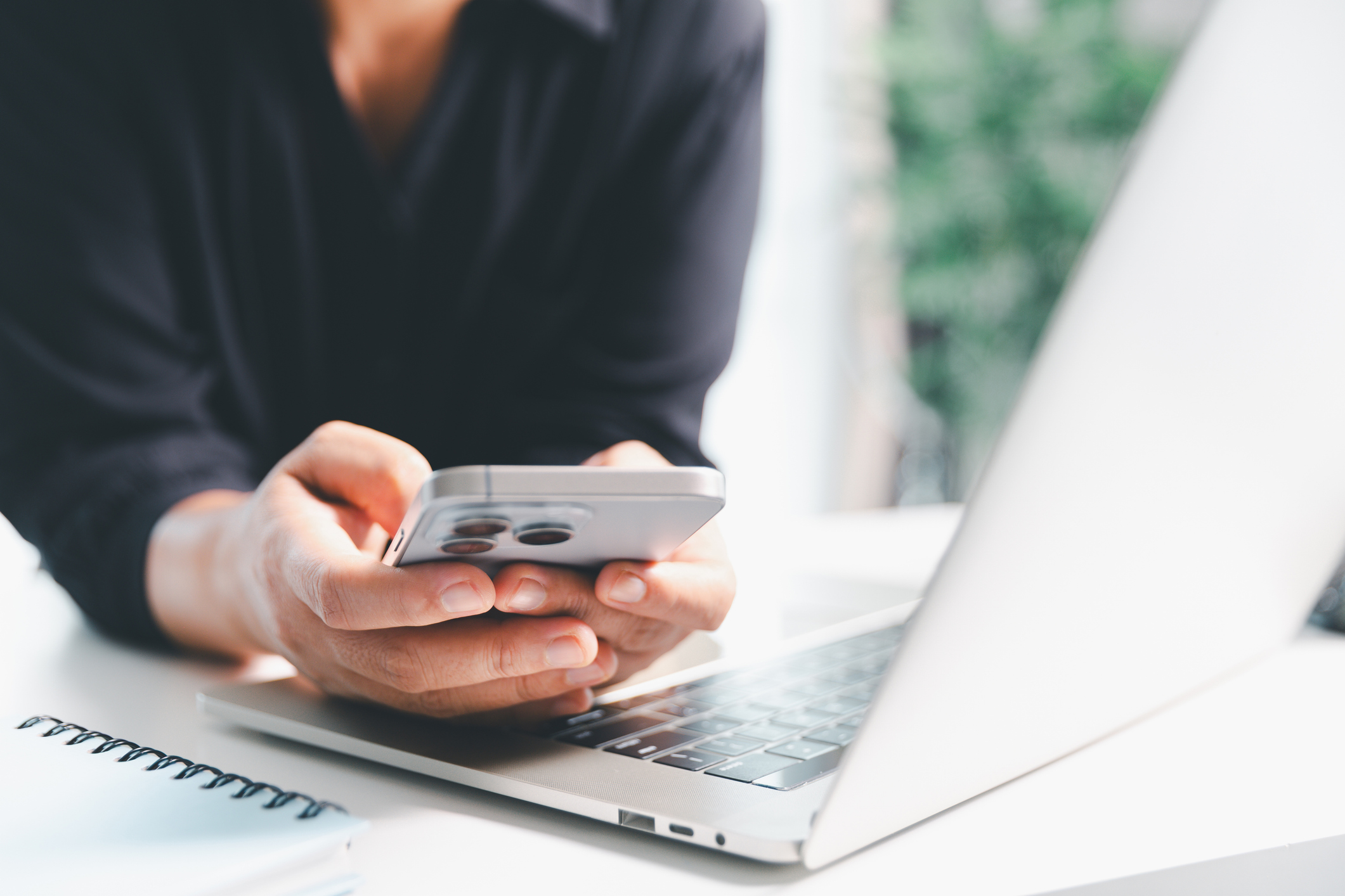 Close-up scene, a female seated at a table holds a smartphone