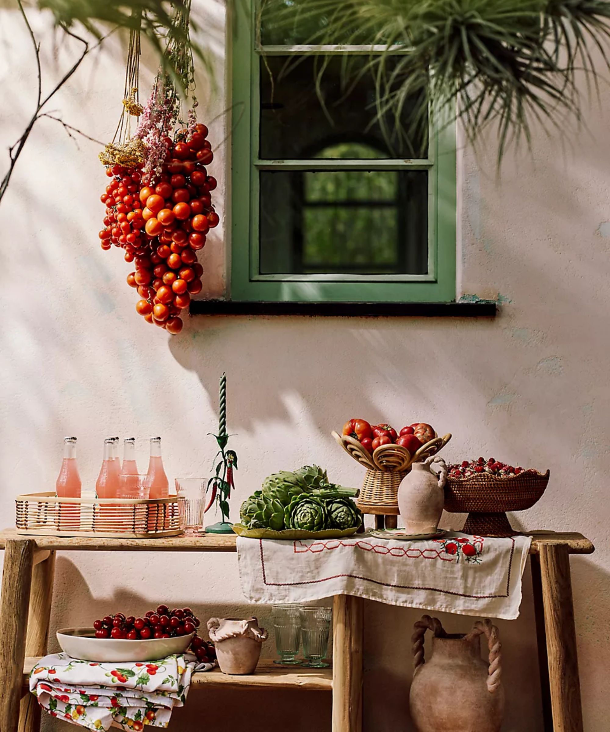 outdoor wooden console table styled as self serve buffet station for a garden party with rattan bowls and a basket of bottle drinks
