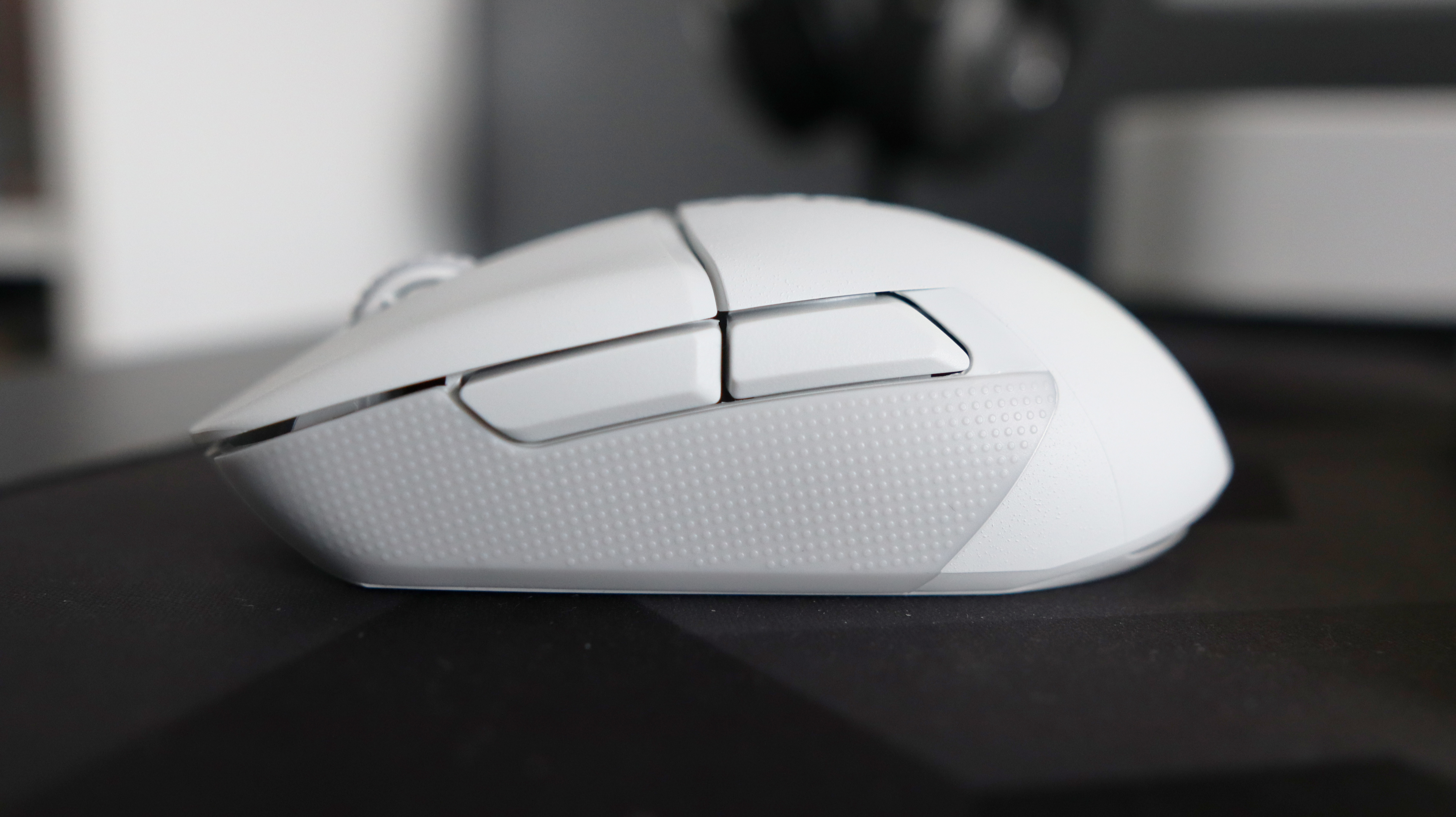 An NZXT Lift Elite Wireless gaming mouse in white set-up on a desk.