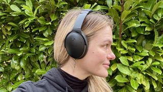 Becca wearing the Bose QuietComfort headphones next to greenery