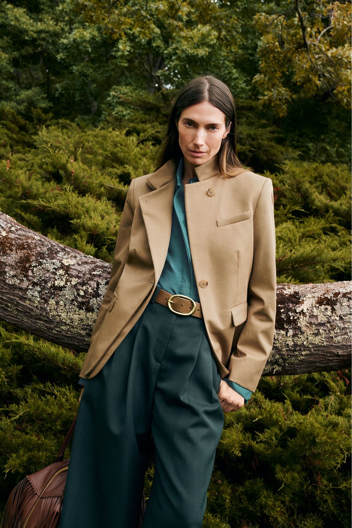 A model shot outdoors wearing a camel blazer and green pants