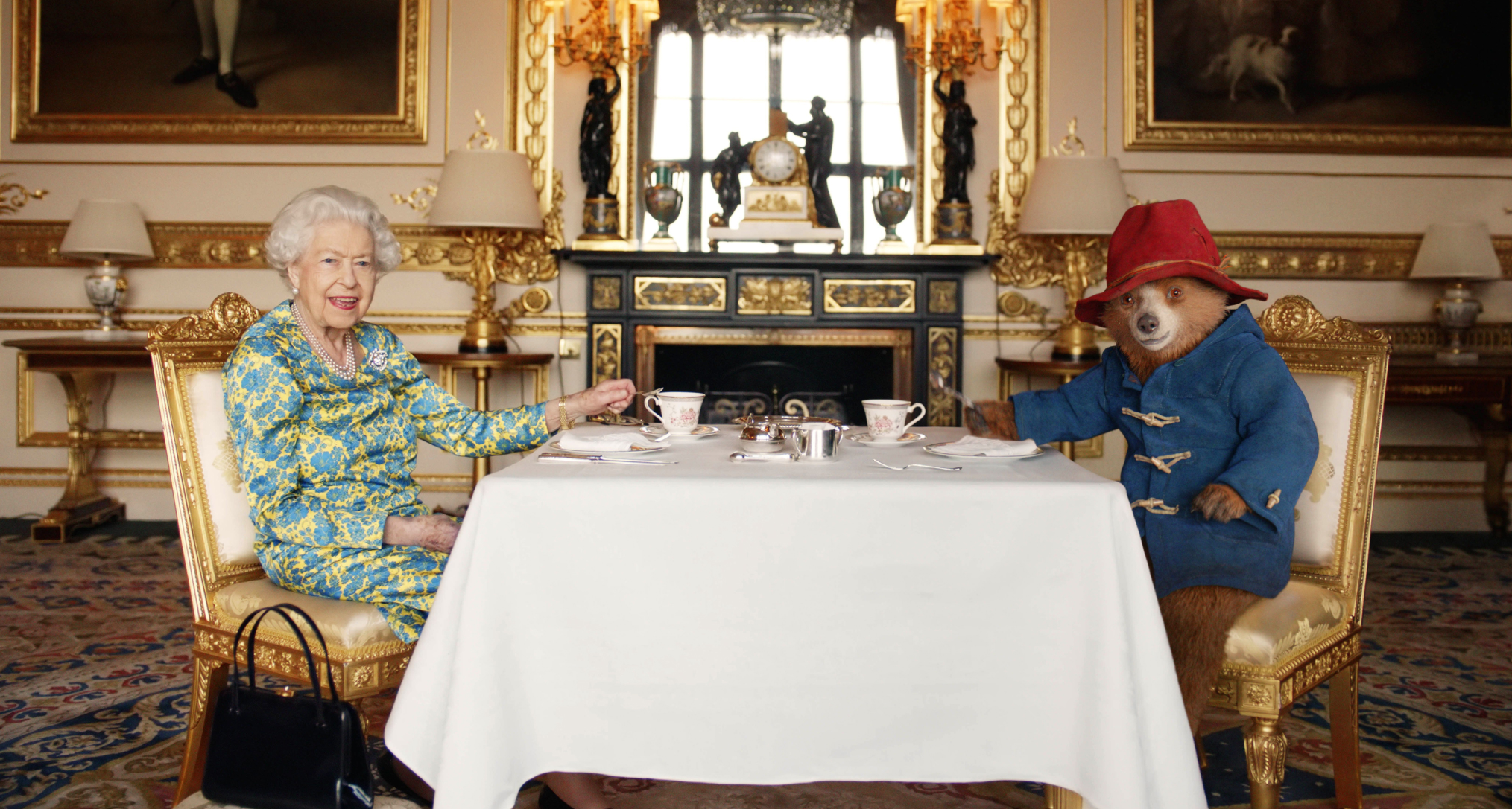 Queen Elizabeth sitting at a table with Paddington Bear