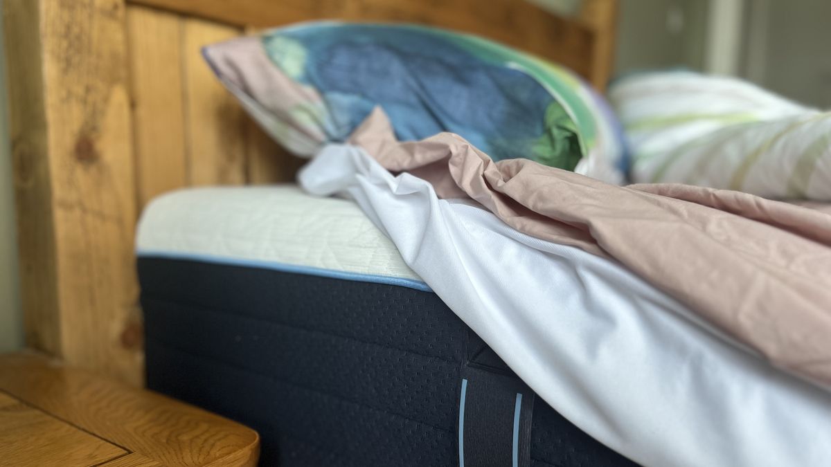 pink fitted sheet and white mattress protector pulled back to show nectar classic hybrid mattress underneath