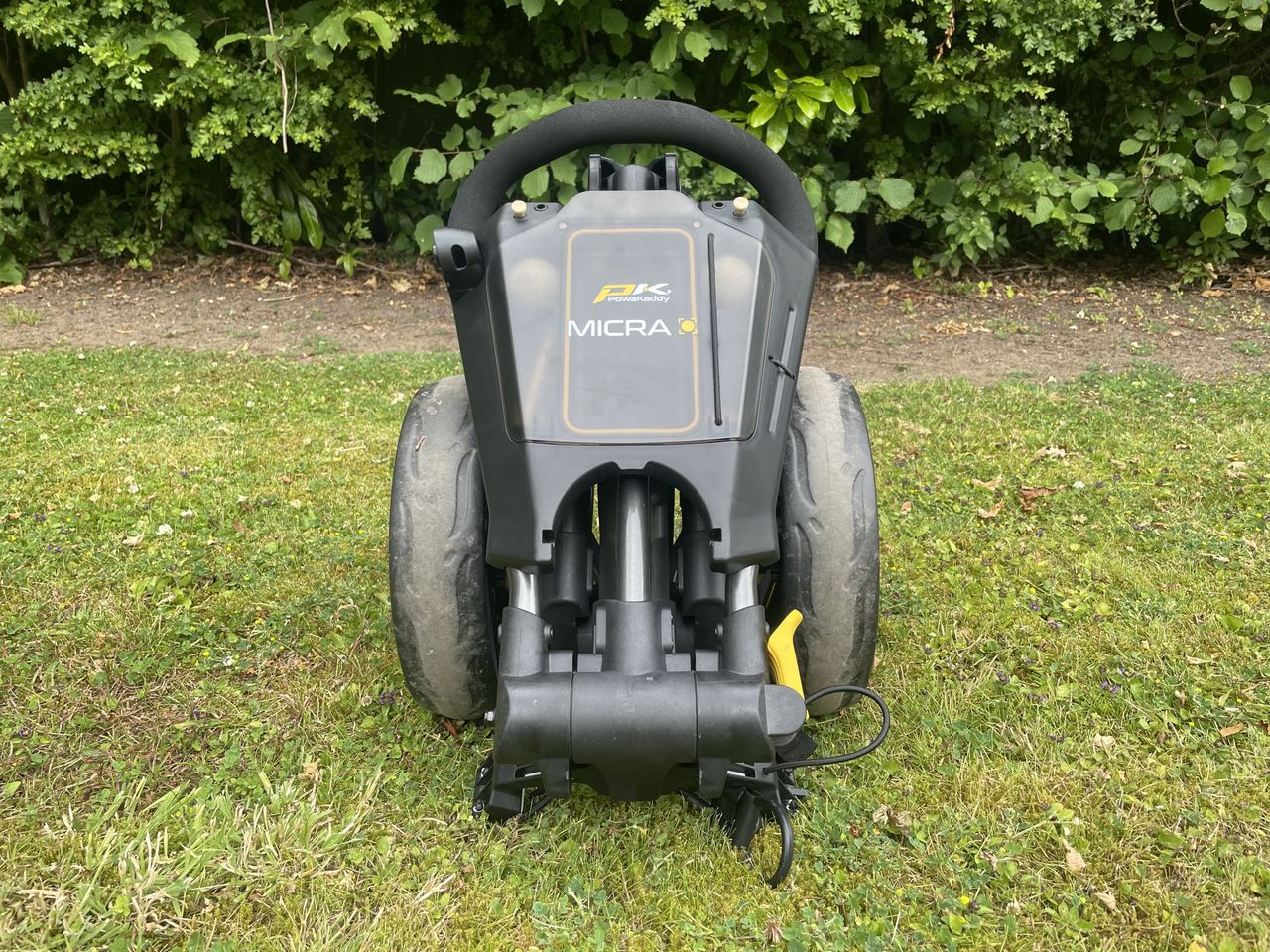 A front view of the PowaKaddy Micra push cart folded up