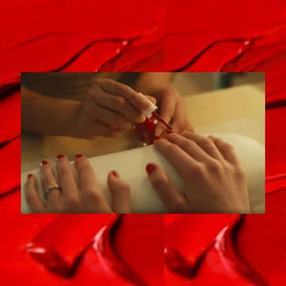 A red background with a still of a woman getting a red manicure