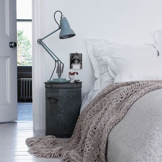 bedroom with side table and lamp and white wall