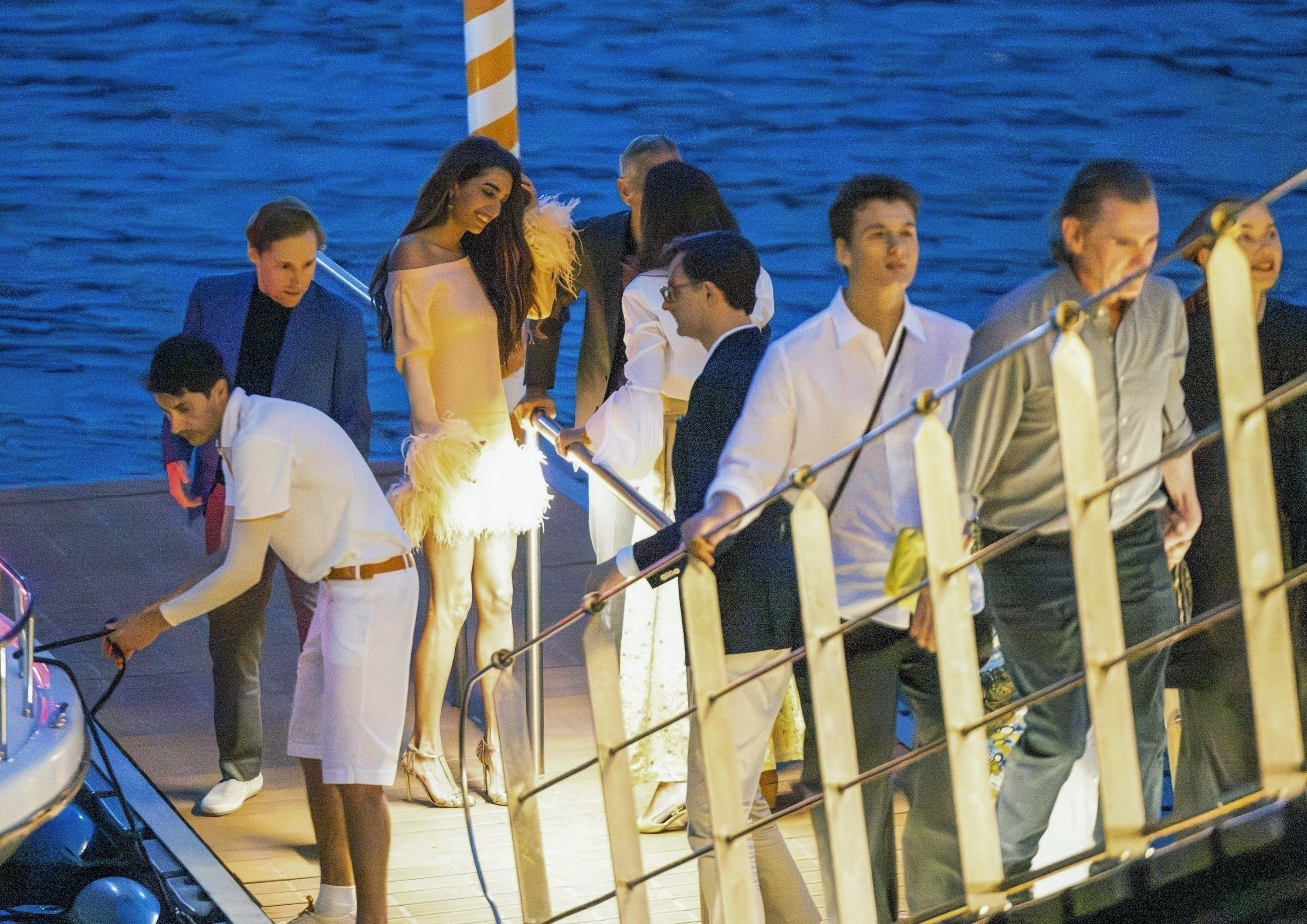 Amal Clooney on a boat in Lake Como wearing yellow feathers