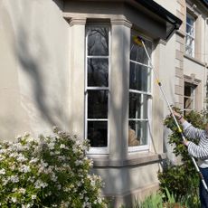woman with an easy clean telescopic hose brush cleaning a window