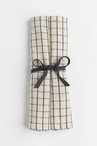 two checkered napkins rolled up and tied together with a black bow