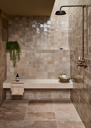 Cream green zellige tiles with a seating area and brass shower fixtures