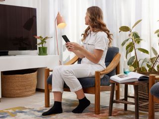 A woman sitting in her sitting room using EE tech