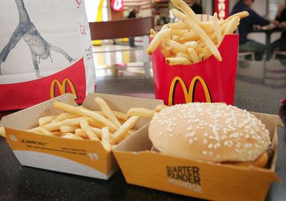 A quarter pounder with cheese sits in front of fries in a McDonald's burger.