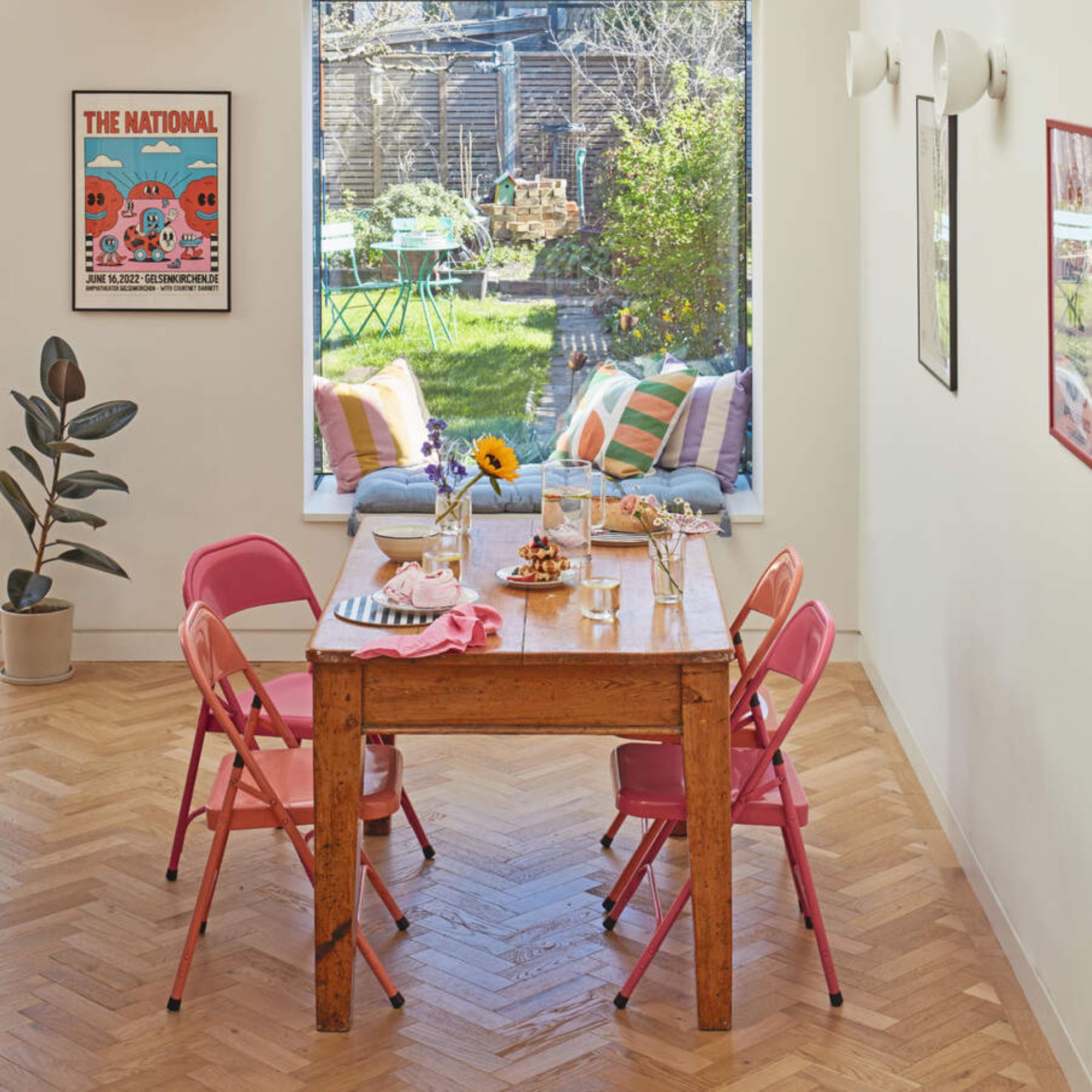 Dining room with herringbone flooring, a wooden dining table and pink metal chairs