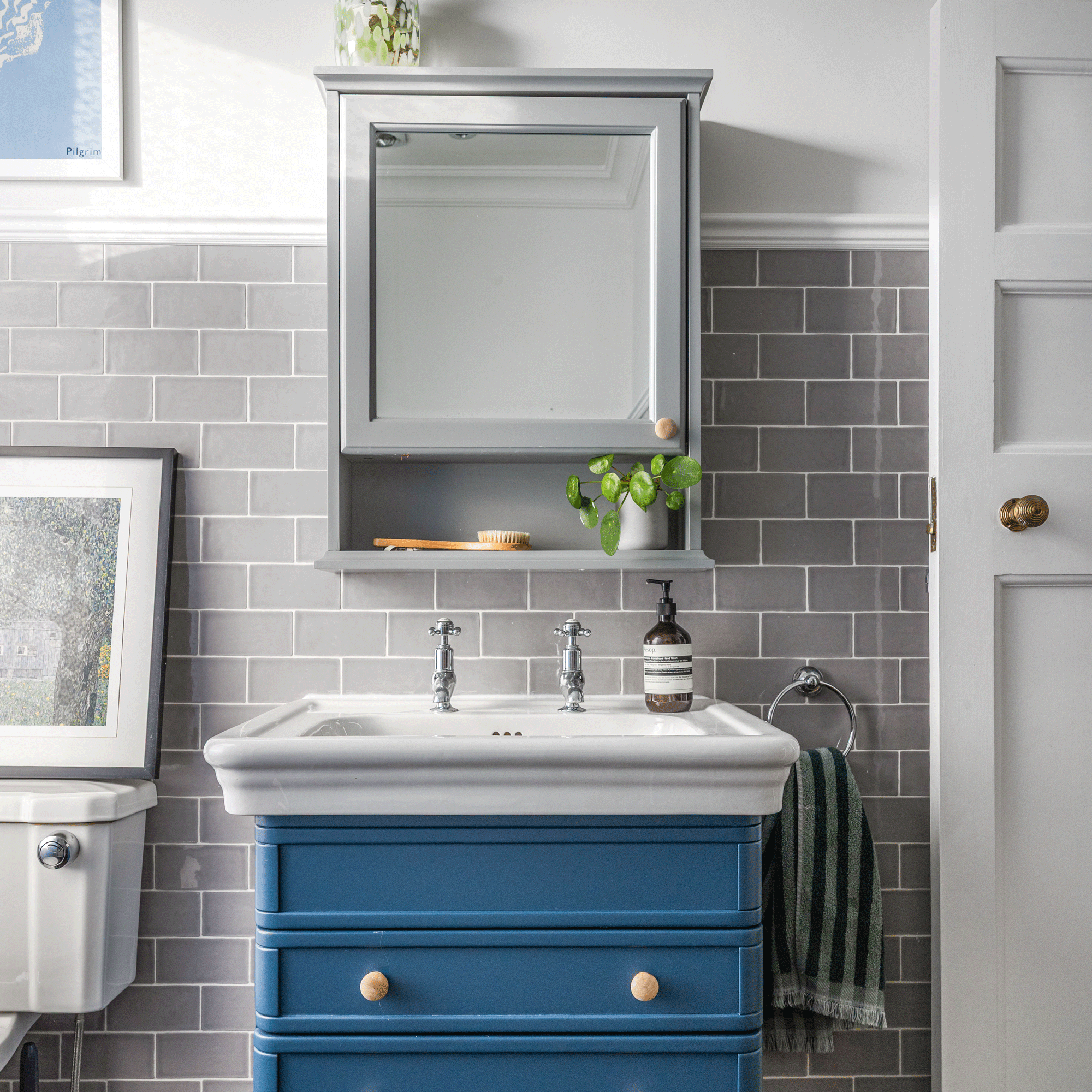 a grey tiled bathroom with white walls and a blue vanity unit