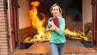 Woman running from burning building holding photo album 