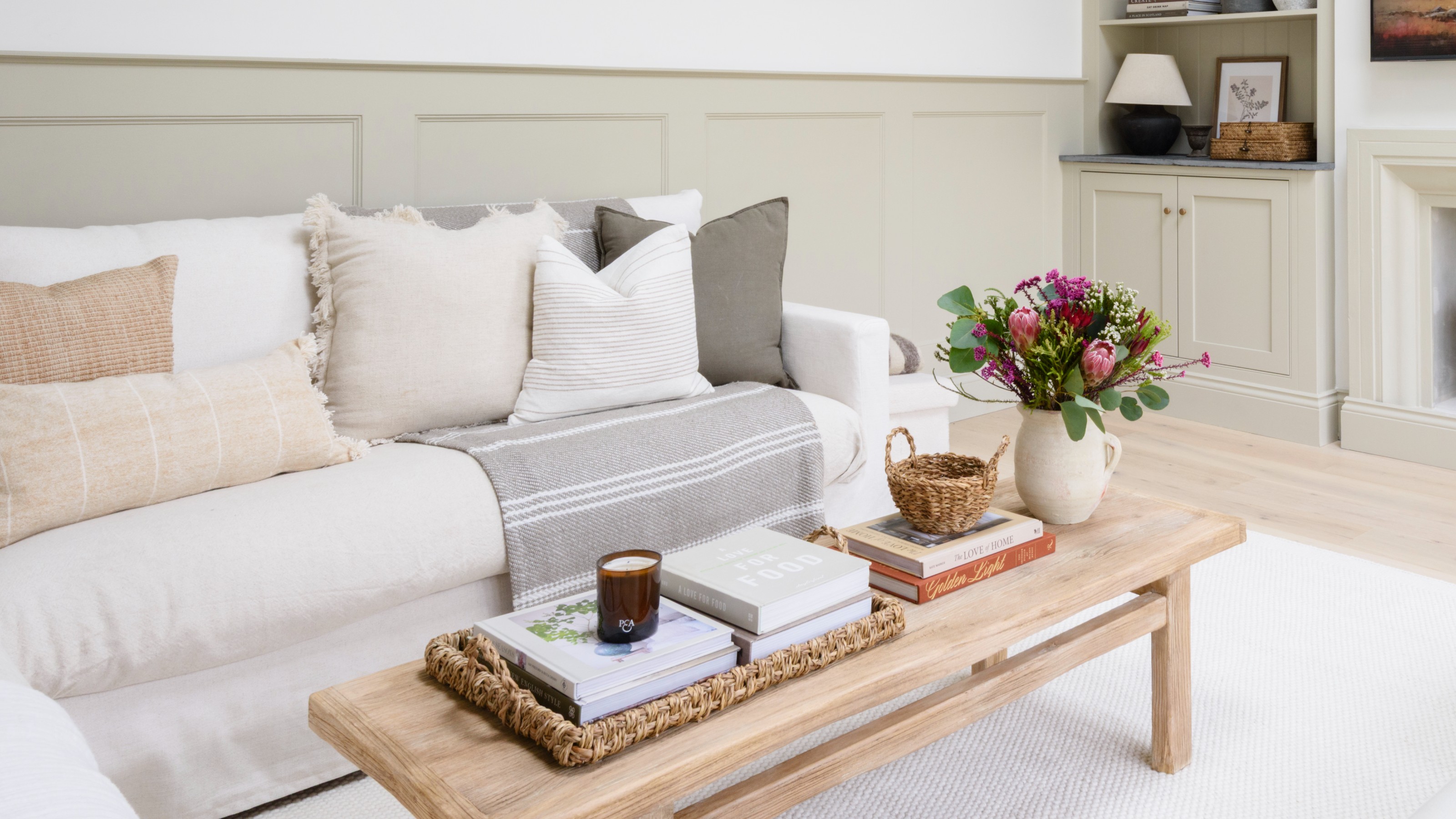 A light and bright living room with dado rail panelling and a wooden rectangular coffee table in front of a cream sofa