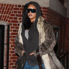 Rihanna wears snake-print boots with jeans, a fur coat, and a hoodie