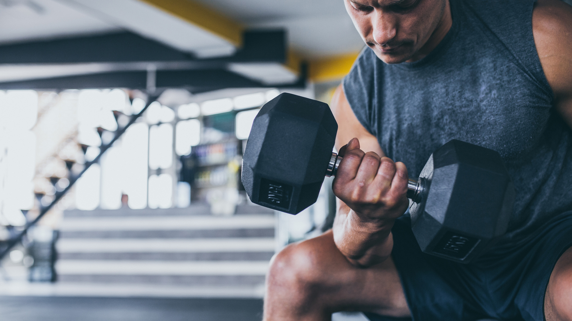 hombre haciendo curl con mancuernas en el gimnasio