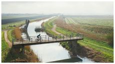 Cyclist crossing bridge over river