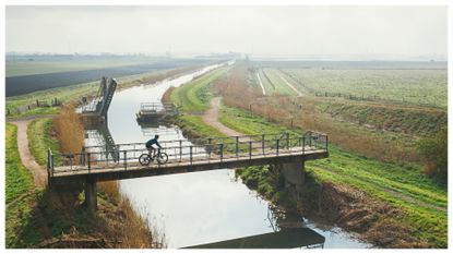 Cyclist crossing bridge over river