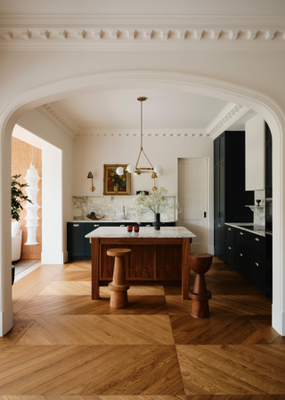 Open plan kitchen area with wooden island and marble counters with matching backsplash