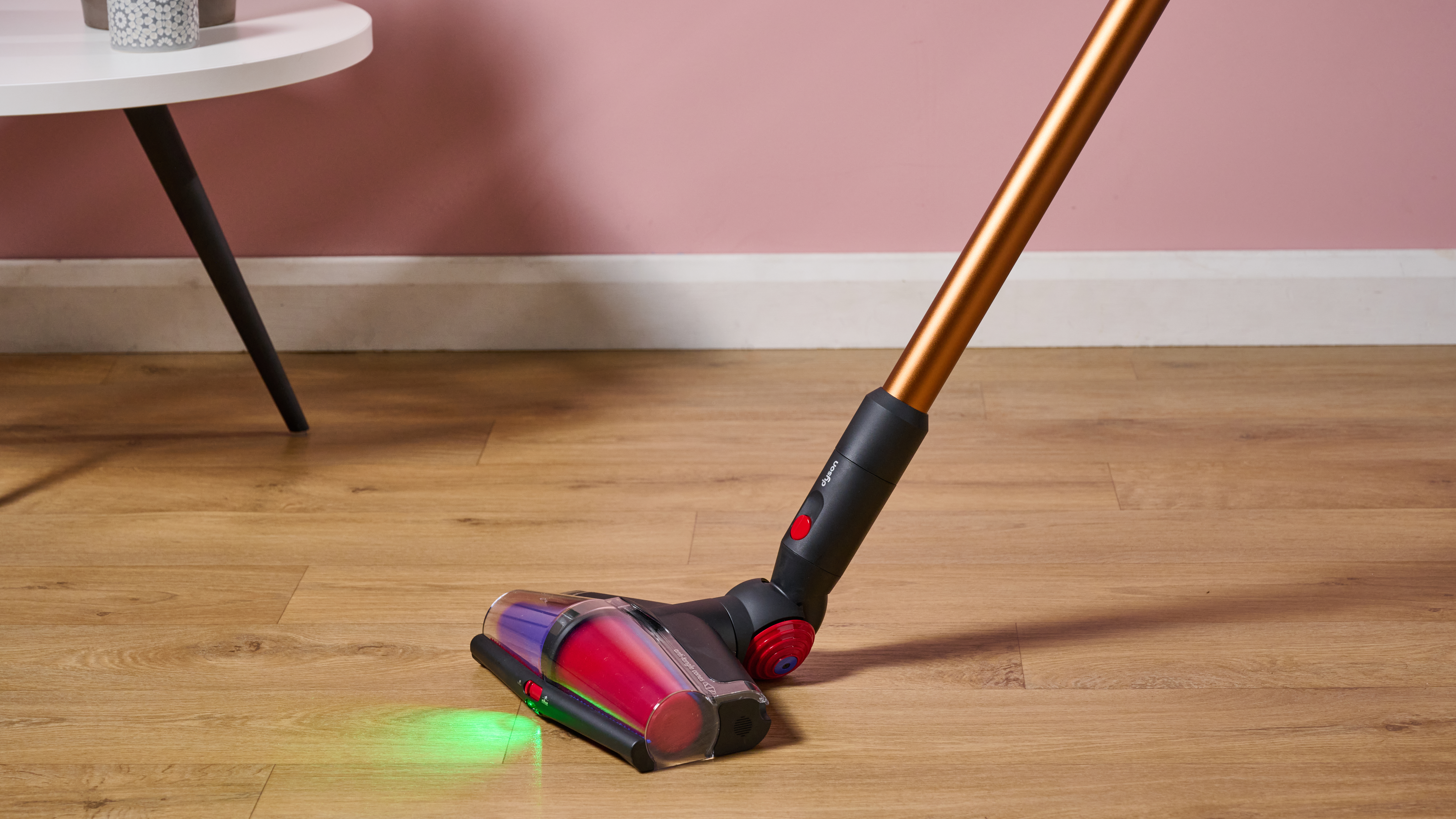 Laser on floorhead of Dyson V16 Piston Animal cordless stick vacuum, illuminating a wooden floor