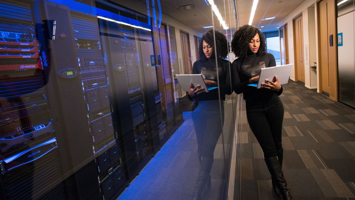 woman on laptop next to data center