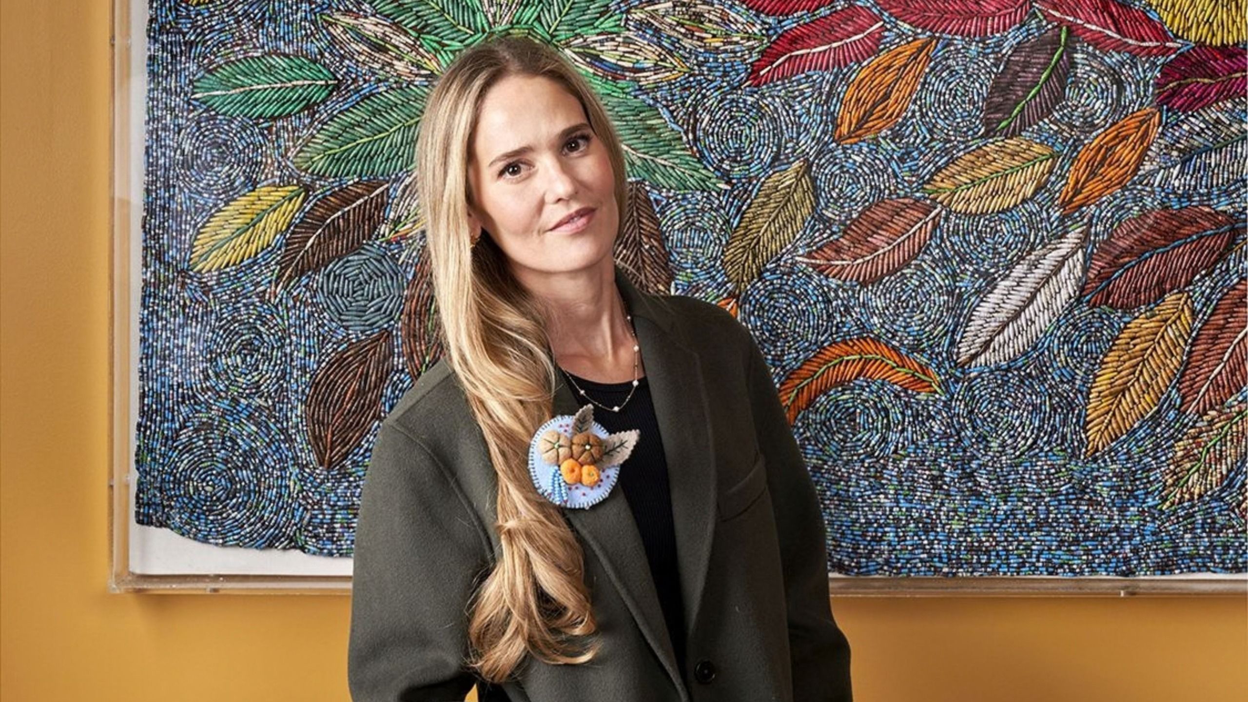 Designer Willow Kemp stood in front of a piece of mosaic artwork